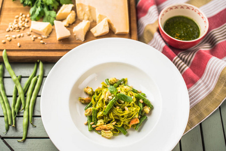 意大利蔬菜意面加Pesto酱，盘子放在木桌上，里面有配料