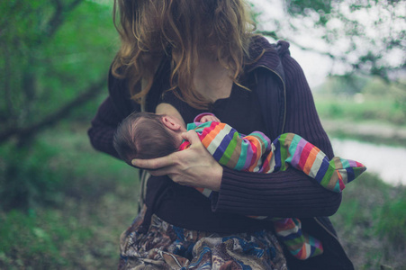 一位年轻的母亲在森林里给婴儿喂奶