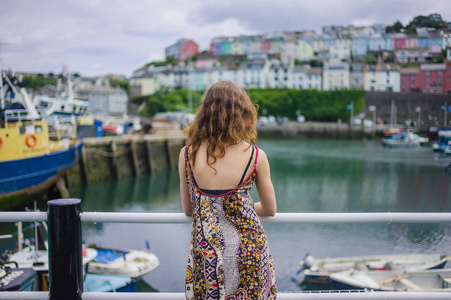 一位年轻女子站在一个小港口的栏杆旁