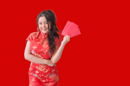 亚洲妇女穿着传统的中国旗袍连衣裙，为中国新年展示红包。