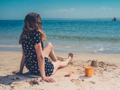 一位年轻女子正在海滩上放松，正在建造沙堡