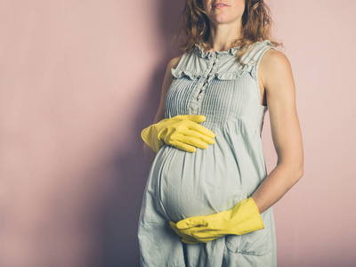 一位年轻的孕妇戴着黄色橡胶手套