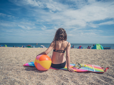 一位年轻女子正拿着一个充气球坐在海滩上