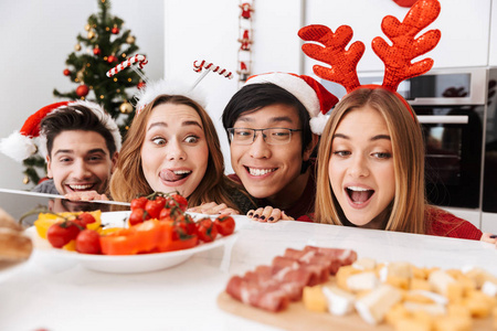 一群快乐的朋友在家里的厨房里庆祝圣诞节，从桌子往外看美味的食物