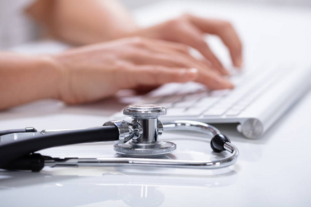 s Hand Using Computer Keyboard With Stethoscope On White Reflect