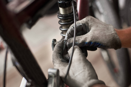 在自行车修理厂工作的男机修工戴防护手套
