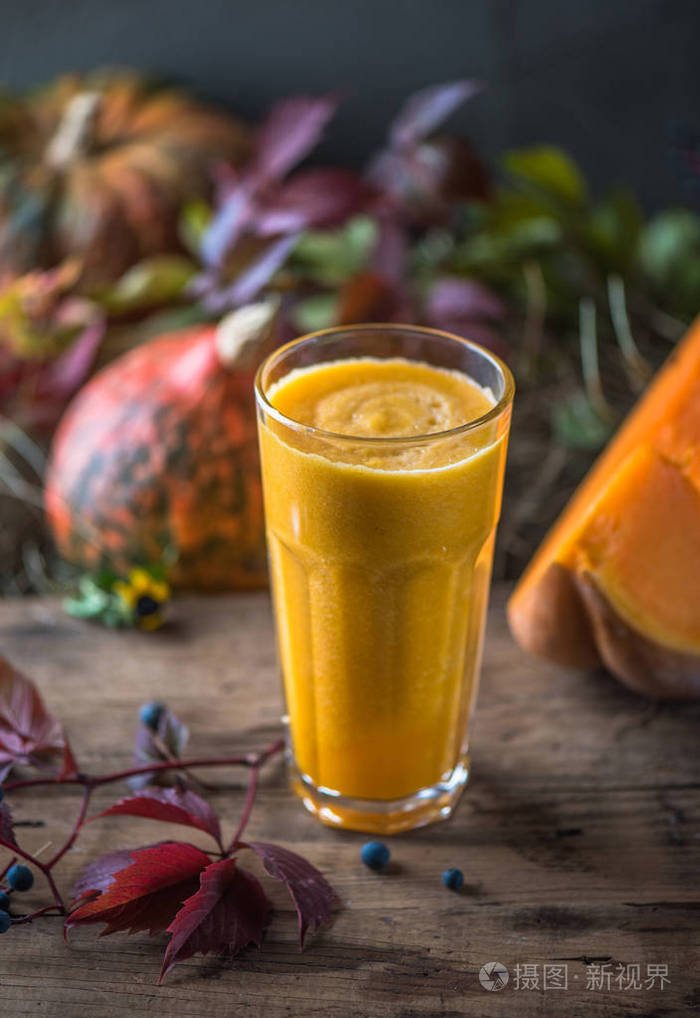 新鲜南瓜冰沙放在木桌上上面有秋叶和浆果