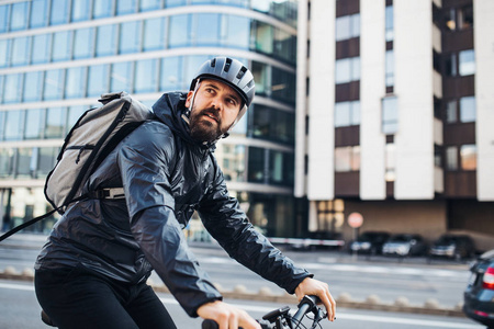 男性快递与自行车运送包裹在城市。复制空间