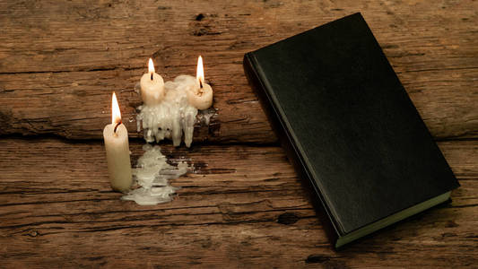 打开圣经和蜡烛在一张老橡木桌上。美丽