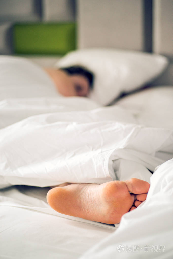 在家里或酒店的卧室里,用白色毯子和床单把女人光着脚关在床上.