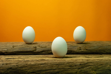 鸡蛋在老橡木桌上橙色背景。