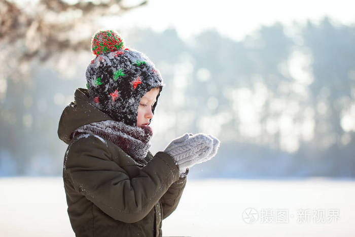 一个可爱的小男孩的肖像,穿着温暖的衣服,在冬天的晴天下雪的时候在