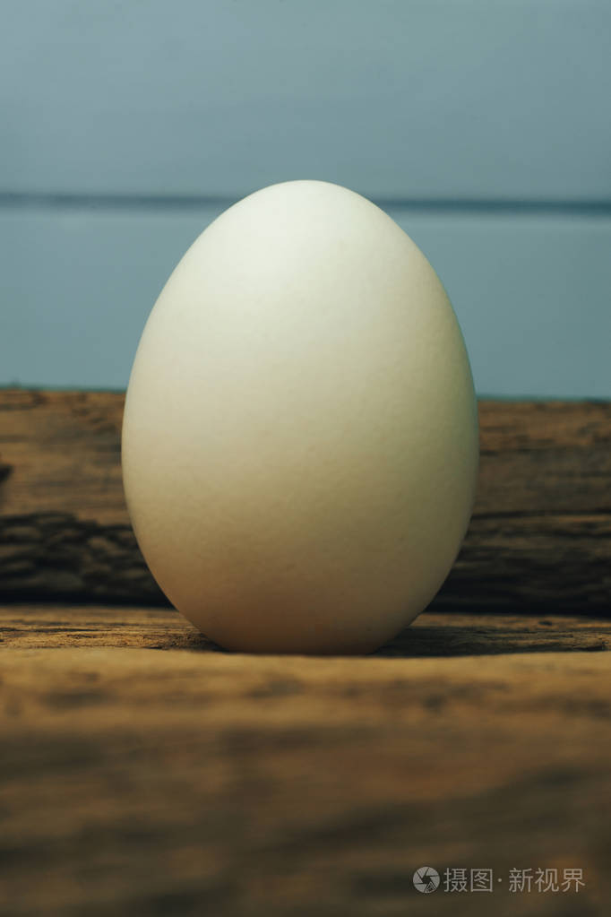 白色鸡蛋在一个古老的橡木木桌蓝色背景