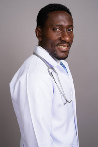 年轻英俊非洲人医生反对灰色背景