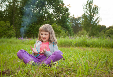 可爱的学龄前女孩坐在夏天的公园里玩肥皂泡