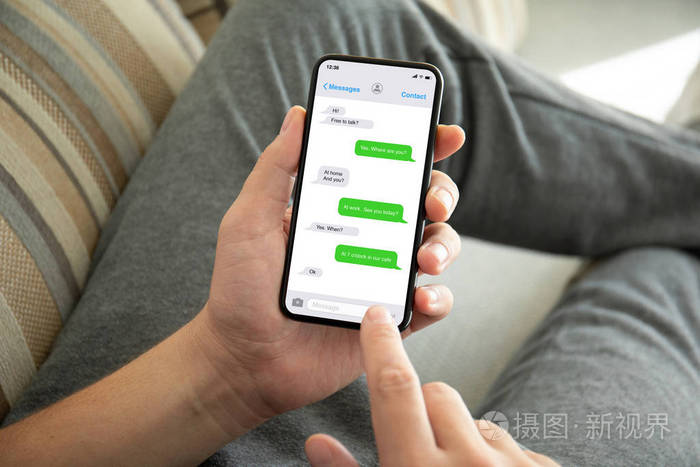 男性手拿电话,应用信使在房间的屏幕沙发上.