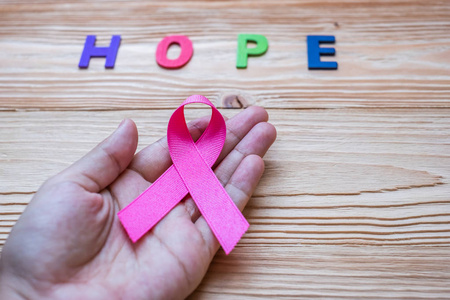 世界癌症日2月4日或乳腺癌希望信和粉红色丝带的木制背景，以支持人们的生活和疾病。 保健和医学概念