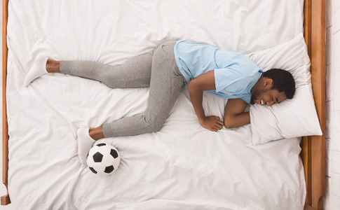 黑人运动员与球睡在床上