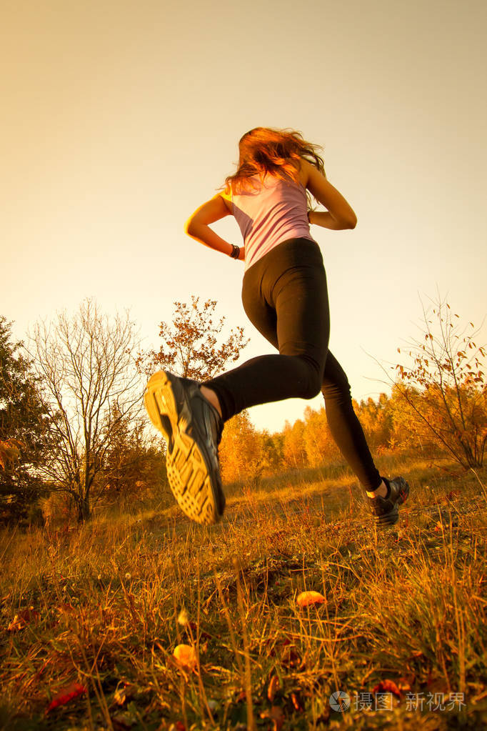 在公园的自然环境中女孩在日落时奔跑和跳跃