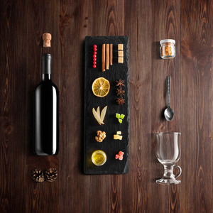 覆盖葡萄酒配方成分和厨房配件瓶红葡萄酒肉桂八角星橙色红糖和香料在乡村木材背景。