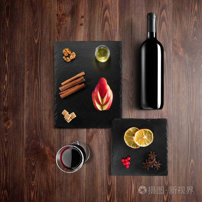 覆盖葡萄酒配方成分和厨房配件瓶红葡萄酒肉桂八角星橙色红糖和香料在乡村木材背景。