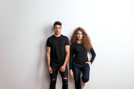 一对年轻夫妇穿着黑色衣服站在演播室里的肖像