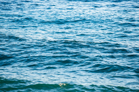 美丽的亚得里亚海海水特写。海浪在阳光下的海滩上翻滚。鲜艳的蓝色