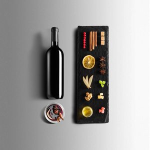 覆盖葡萄酒配方成分和厨房配件瓶红酒肉桂八角星橙色红糖和香料灰色背景。