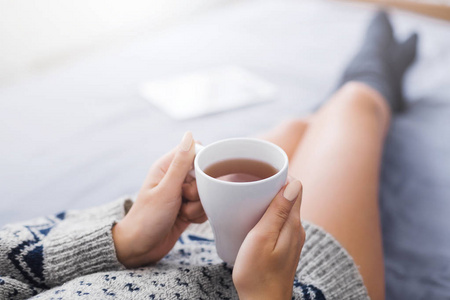 妇女休息在床上与一杯茶