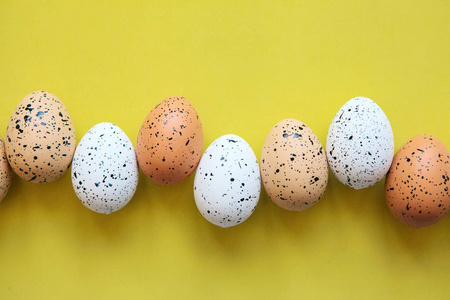 一排黄色背景上的一组有色鸡蛋。节日复活节概念