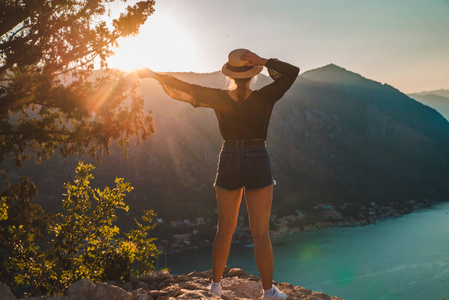 站在山顶上的女人。 背景上有日落的Kotor。 夏季旅行概念