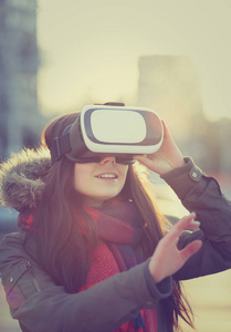 年轻女性玩创新的虚拟现实眼镜用于移动游戏应用。使用带有创新3D耳机的移动游戏应用程序。现代增强现实游戏玩家小工具。可爱的女孩在V