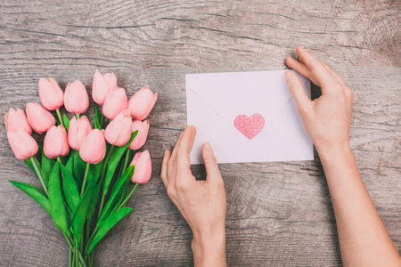 s hands are holding a blank envelope with a heart, on a wooden b