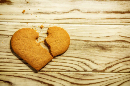 破碎的心形姜饼干和面包屑的木制背景爱的概念