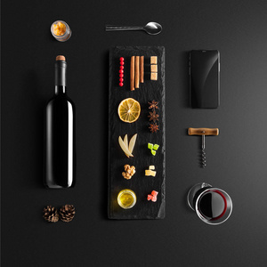 覆盖葡萄酒配方成分和厨房配件瓶红酒肉桂八角星橙色红糖和香料黑色背景。