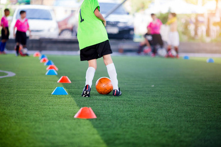 足球运动员跳跃和踩踏训练，以陷阱和控制足球。 儿童足球运动员慢跑和跳之间的圆锥标记足球训练。