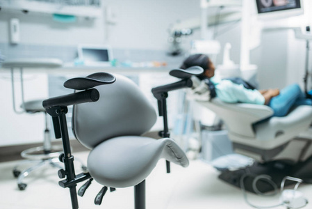 女性病人坐在牙科诊所后景的椅子上。 口腔科口腔科口腔科口腔科的女性
