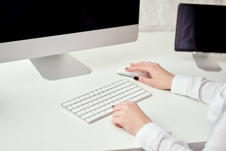 在办公室工作和使用电脑的白色键盘上打字的模糊女性手的特写镜头