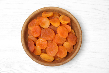 木制碗与干燥杏在白色桌面视图。 健康水果