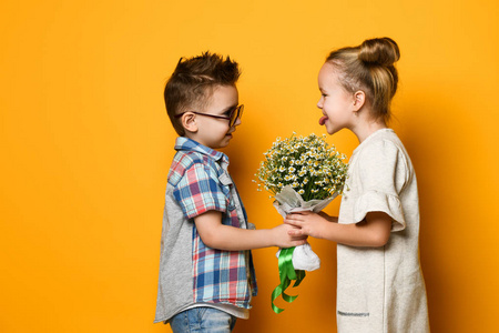 愉快的高加索人男孩给他的女朋友一朵花孤立在黄色背景