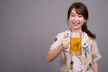 年轻美丽的亚洲旅游妇女拿着一杯啤酒