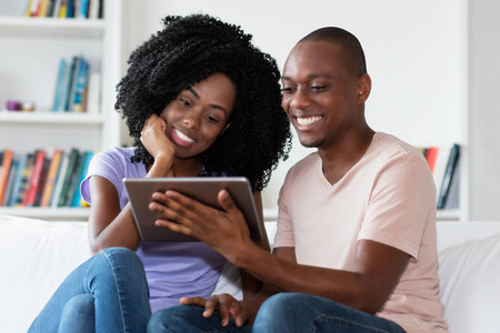 非裔美国人夫妇在家里用平板电脑看电影