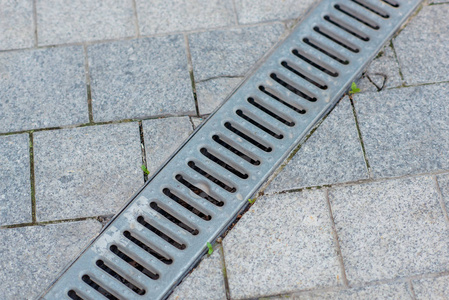 铺上灰色的石板. 用金属烤架排水人行道. 下水道排水. 排水要素.