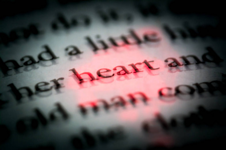 英语书中的心这个词用红色突出显示了宏。 书中的文本具有三维效果。 复古复古风格的照片。