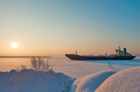 阿汉格尔斯克。 阳光明媚的冬日在北部的德维纳河岸。 一月。 商船在Arkhangelsk港航道上的冰中。