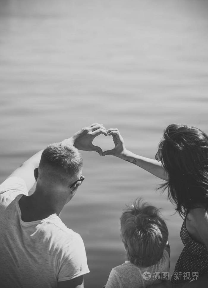 母亲和父亲在他们的孩子附近做心脏或爱手势与手.父母与儿子, 后视.