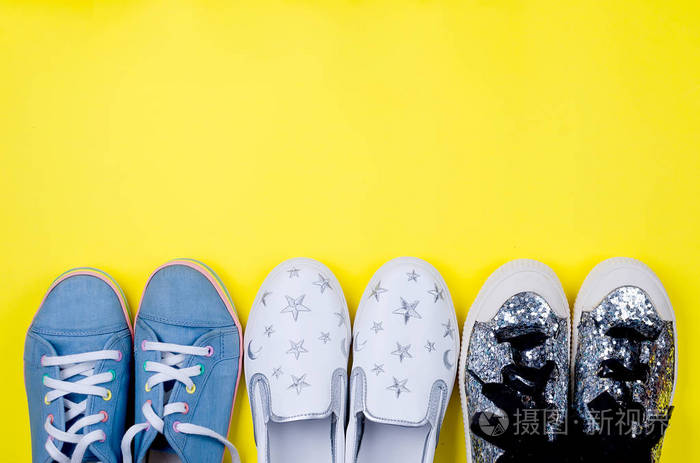 三双不同的鞋为一个十几岁的女孩帆布滑鞋运动鞋黄色背景.