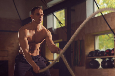 适合运动和运动运动员在健身房工作。 使用战斗绳索训练的人。 体育竞技生活方式和健身理念。