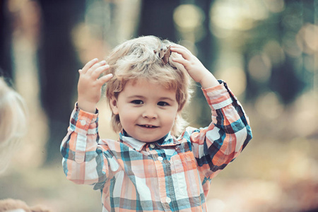小快乐男孩玩树叶在金黄秋天公园背景