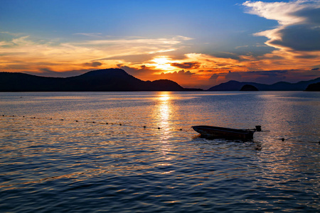 小渔船在海上日落的景色，美丽的景观和大自然的光在晚上与美丽的颜色，云彩和天空。